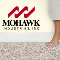 A person standing on the ground in front of mohawk industries logo.